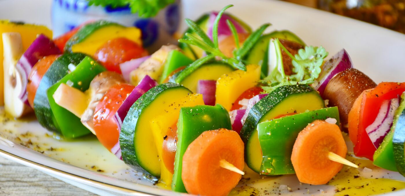 Drei vegane Gemüsespieße liegen auf einem Teller